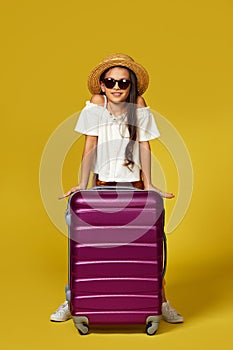 Happy little child girl in hat with pink suitcase