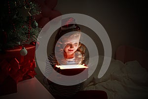 Happy little child girl holding a magical Christmas box with a gift