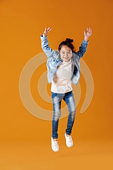 Happy little child girl in jeans clothes jumping