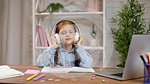 Happy little child girl is listening to music on headphones.