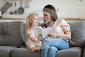 Happy little child girl reading interesting books with mom.