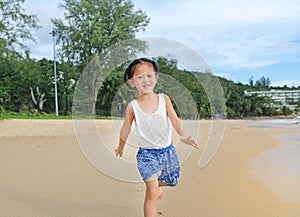 Happy little child girl running on the beach in summer times