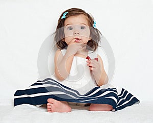 Happy little child girl sit on white towel, happy emotion and face expression, very surprised, the finger in mouth