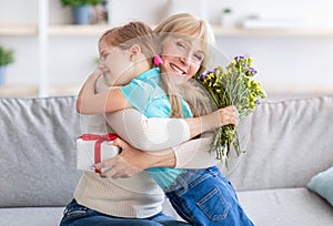 Happy little child greeting happy aged woman with flowers