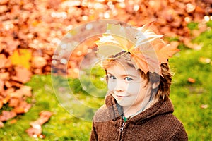 Happy little child have fun and playing with fallen golden leaves.