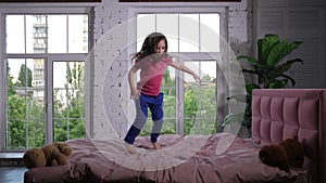 Happy little child jumping on cozy bed in bedroom