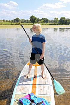 Happy Little Child Learning to Stand Up Paddle Board on Summer Day