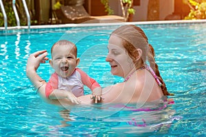 Happy little child with mother, Baby first time in a large pool and very impressed. Infant very happy and frolic