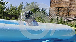 A happy little child plays with a ball in an inflatable pool with water