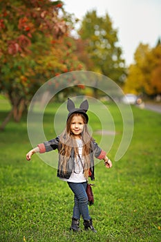 Happy little child posing for the camera, baby girl laughing and playing in the autumn on the nature walk outdoors.