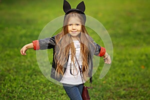 Happy little child posing for the camera, baby girl laughing and playing in the autumn on the nature walk outdoors.