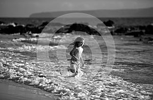 Happy little child running on the tropical beach. Boy playing sea waves on vacation sea in the summer holiday. Kid in