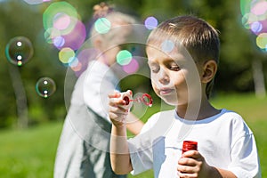 Happy little children blow soap bubbles