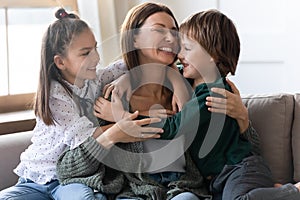 Happy little children hug young mom showing love