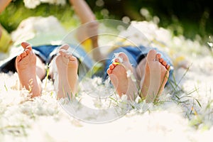 Happy little children, lying in the grass with feathers , barefoot, playing happily, childhood happiness concept.