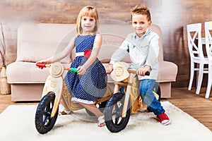 Happy little children riding a runbikes at home