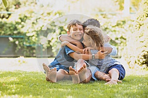 Three little kids are hugging together outdoors