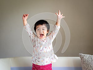 Happy little cute girl laughing and raise the hand up on the sofa. Happy, Children, Family Concept.