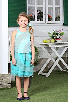 Happy little cute girl in skirt stands near white table