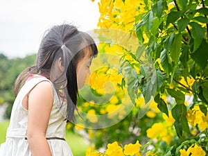 Happy little cute girl smelling the flower in the park in sunny day. Children, Family, Funny Concept.