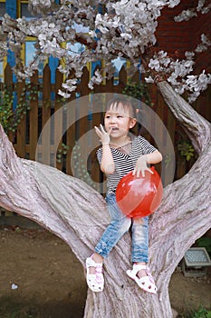 Happy little cute lovely girl Chinese child smile laugh play red balloon have fun at summer park nature happiness childhood