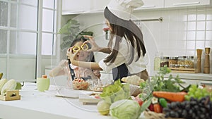 Happy little daughter and mother prepare dinner healthy food having fun