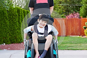 Happy little disabled boy outdoors in wheelchair