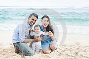 happy little family smiling on camera while vacation on the beac