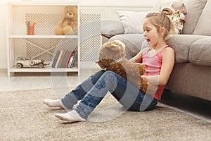 Happy little female child hugging her teddy bear on the floor at home
