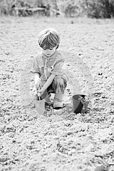 Happy little gardener with spring flowers. Happy kids work plant and water in green spring garden.