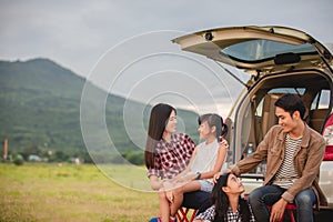 Happy little girl  with asian family sitting in the car for enjoying road trip and summer vacation in camper van