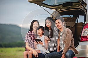 Happy little girl  with asian family sitting in the car for enjoying road trip and summer vacation in camper van