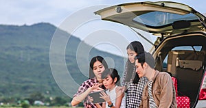 Happy little girl  with asian family sitting in the car for enjoying road trip and summer vacation in camper van