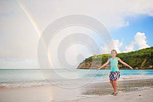 Happy little girl backgound the beautiful rainbow over the sea. Beautiful rainbow on caribbean beach