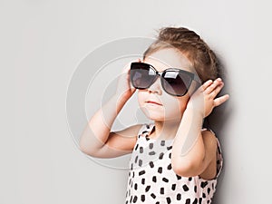 Happy little girl with big sunglasses. Fashionable baby