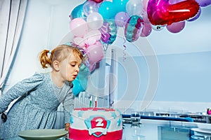 Happy little girl blow candles on the birthday cake party