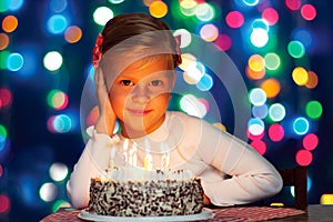 Happy little girl blows out the candles on the cake