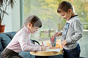 Happy little girl and boy drawing at home