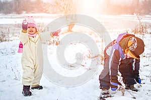 Happy little girl and boy playing in the snow on cold winter day.