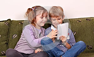 Happy little girl and boy playing with tablet