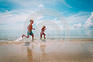 Happy little girl and boy run and play with water at beach