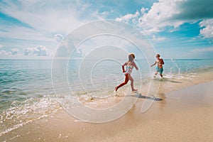 Happy little girl and boy run and play with water at beach