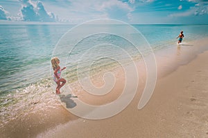 Happy little girl and boy run and play with water at beach