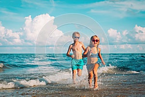 Happy little girl and boy running at beach