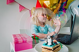 Happy little girl celebrating birthday at home with family on video call