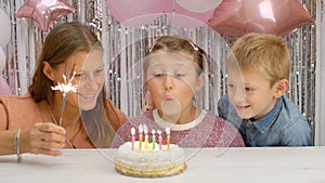 Happy little girl celebrating her birthday with family blowing out the candles on her cake. her family  watching little child