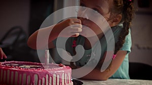 Happy little girl celebrating her birthday with family blowing out the candles on her cake. Parents and grandparents