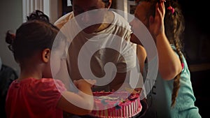 Happy little girl celebrating her birthday with family blowing out the candles on her cake. Parents and grandparents