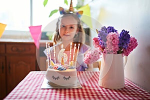 Happy little girl celebrating her sixth birthday and making a wish. Little kid with birthday cake and candle