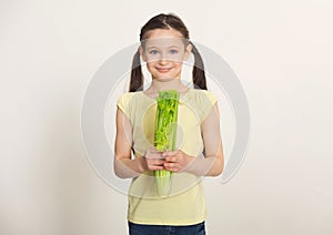 Happy little girl with celery over white background